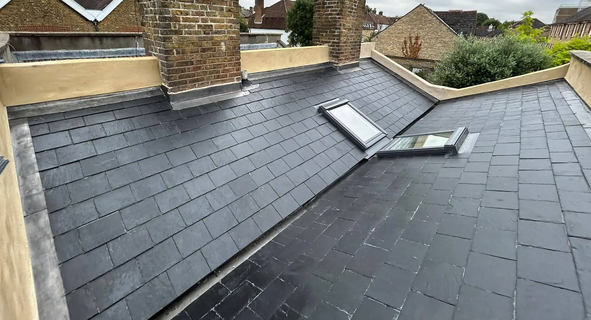 Slate roof installation by roofing services in South West London showing new tiles, leadwork and Velux windows.